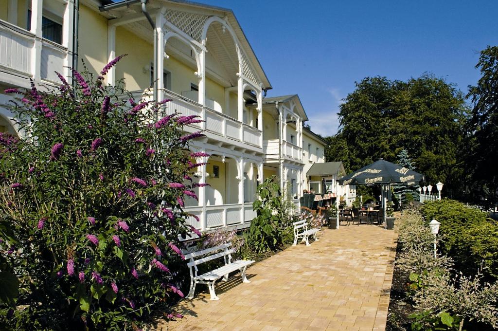 奥斯赛拜-塞林森林酒店的一座白色的大建筑,花色紫色,长凳