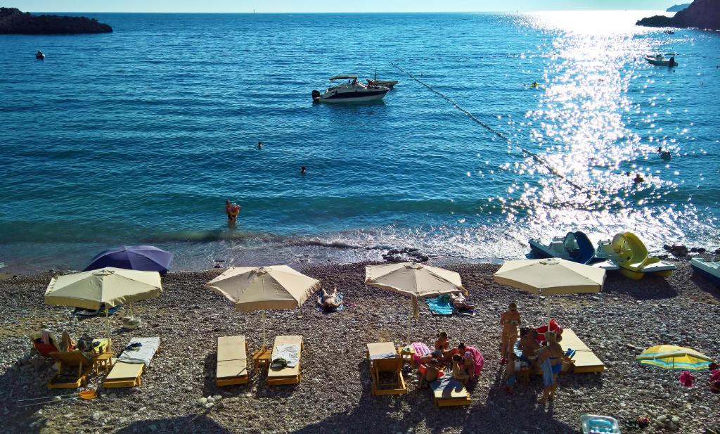 斯韦蒂·斯特凡Apartments Zezelj的海滩上设有椅子和遮阳伞,水中设有船只