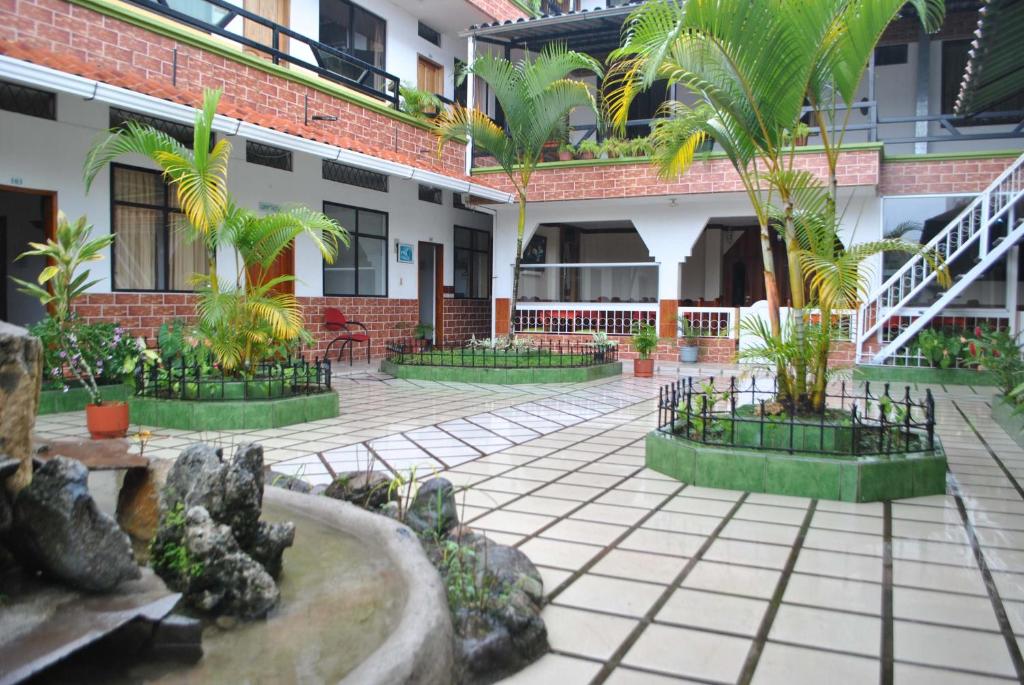 ArchidonaPalmar del Rio Gran Hotel的一座楼前种有棕榈树的庭院
