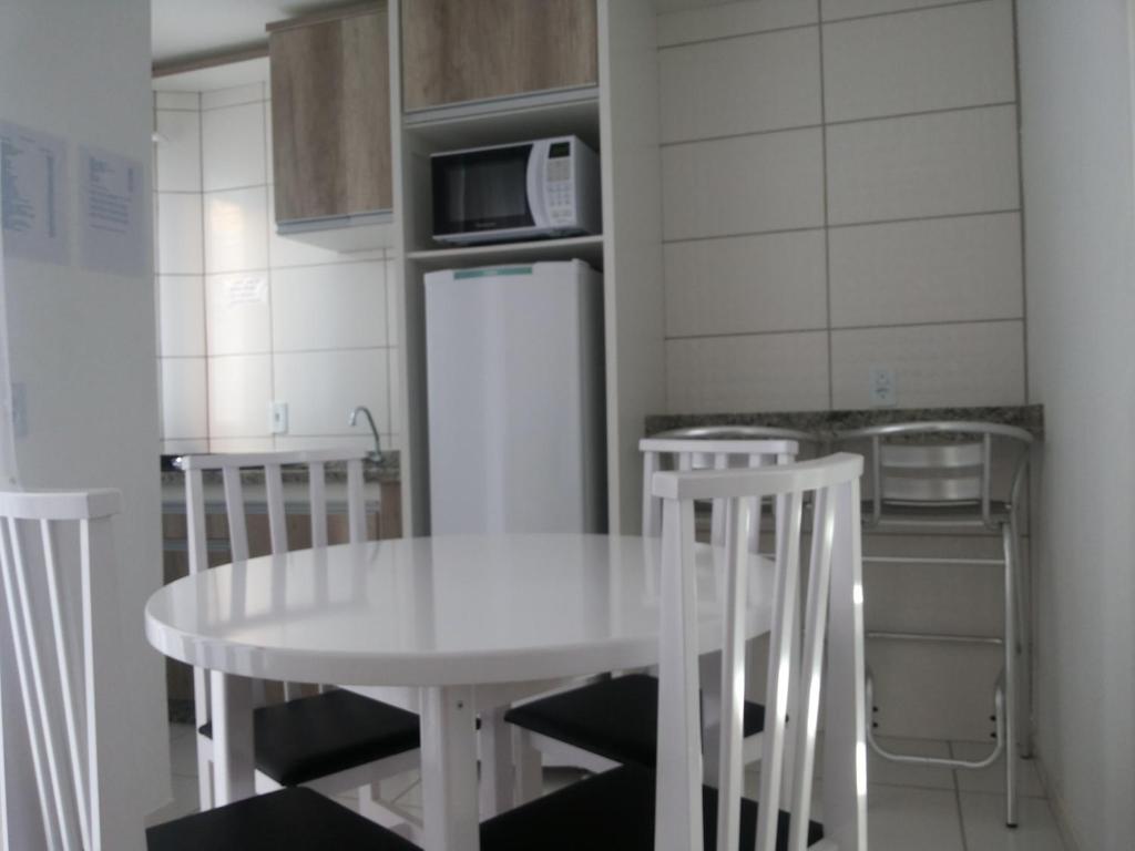 弗洛里亚诺波利斯Residencial Neto的厨房配有白色的桌椅和微波炉