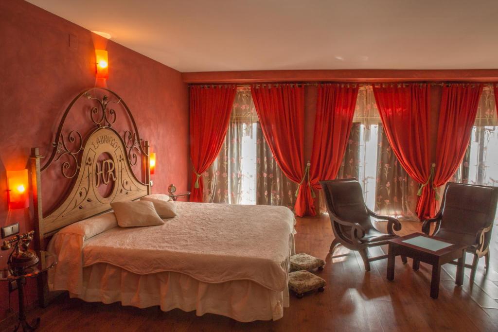 PlasenzuelaHotel Rural El Labriego by Vivere Stays的一间卧室配有大床和红色窗帘