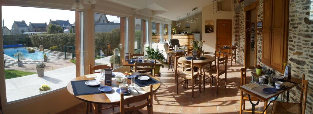 圣伯努瓦德斯昂德La Grande Mare的餐厅设有桌椅和大窗户。