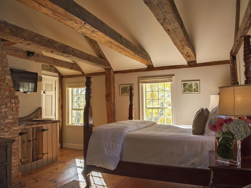 达勒姆三烟囱旅馆的卧室配有一张床铺,位于带木梁的房间