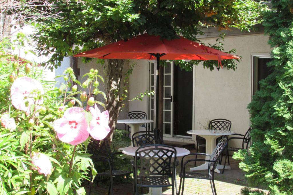 滨湖尼亚加拉Blairpen House Country Inn的一个带桌椅的红色遮阳伞下庭院
