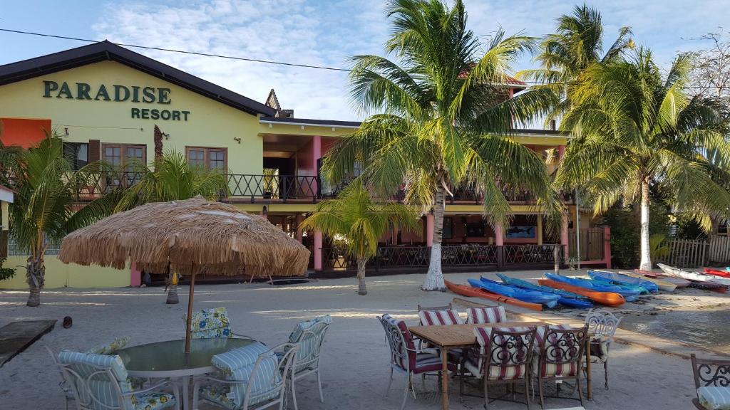 珀拉什奇亚Alan's Paradise Hotel的一间设有桌椅的餐厅,种植了棕榈树