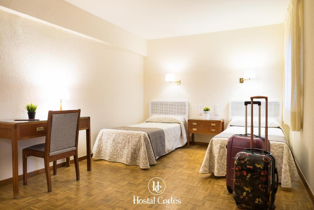 昆卡科尔特斯旅馆的酒店客房带两张床和一张带手提箱的书桌