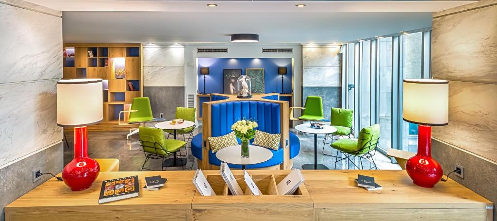 雅典爱若特亚里山德斯酒店的一间设有桌子和绿色椅子的房间和一张带两盏灯的桌子