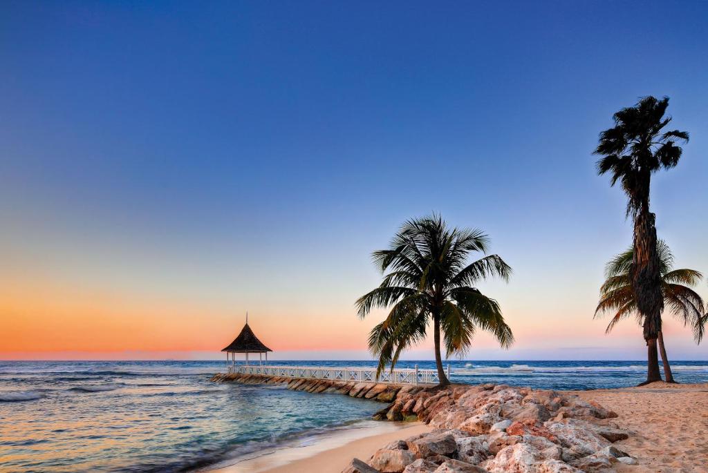 蒙特哥贝半月度假村的日落时分海滩上的两棵棕榈树