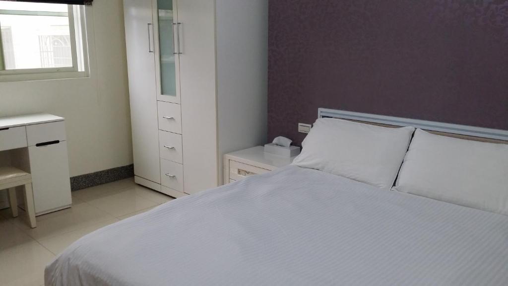 金宁乡爱玩客107的卧室配有白色的床和窗户。