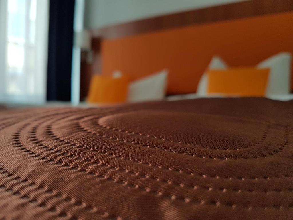 施特拉尔松德Hotel Amber Altstadt的床上的棕色床罩的贴近