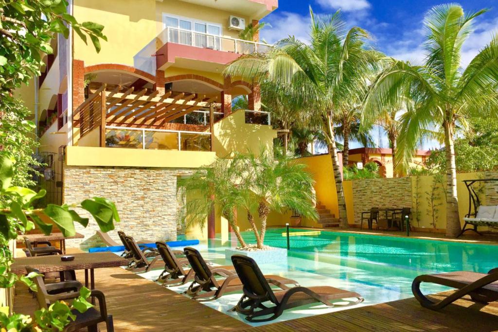 苏莎亚Sosua Inn Hotel的一座带游泳池和椅子的度假村和一座建筑