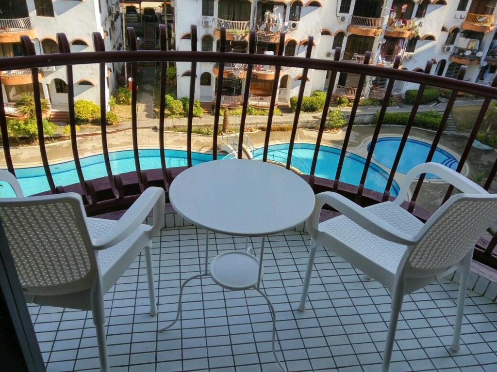 瓜埠皮诺广场公寓的一个带桌椅的阳台和一个游泳池