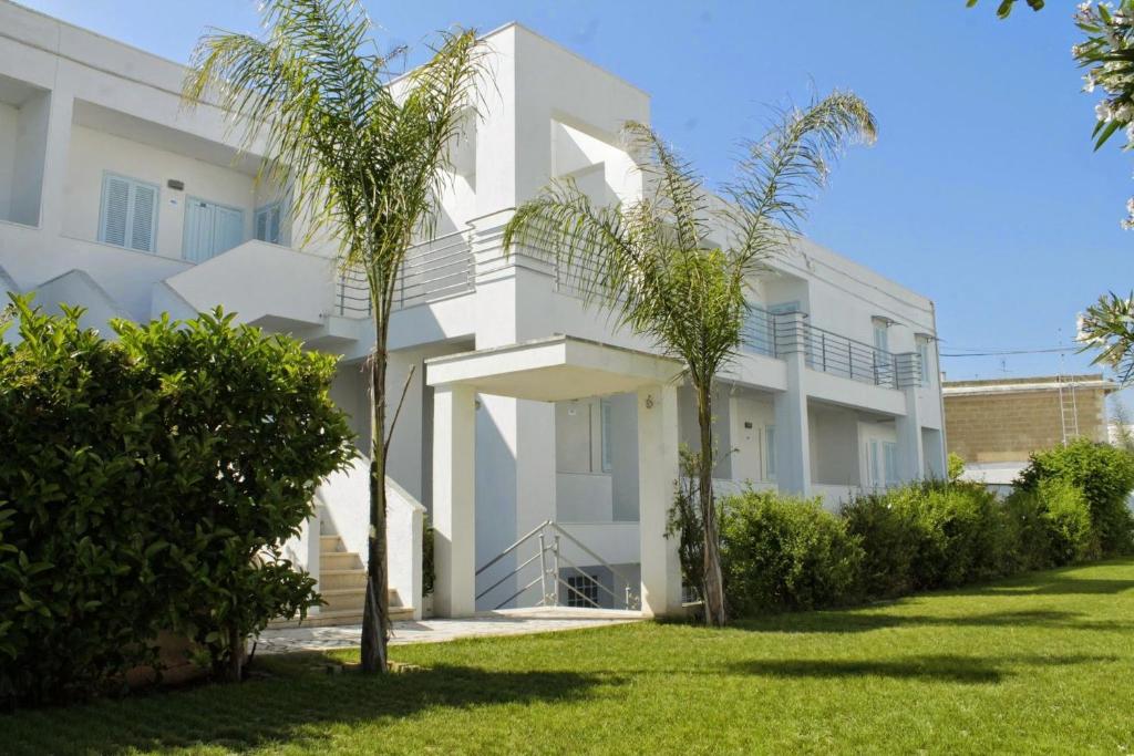 奥斯图尼布露玛丽奈住宅俱乐部酒店的一座白色的建筑,前面有棕榈树