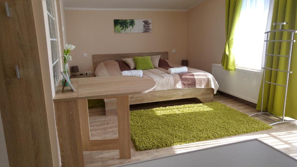 伦蒂Bundics Vendégházak的一间卧室配有一张床和一张桌子,铺有绿色地毯