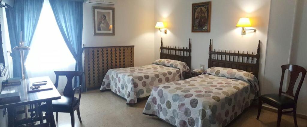 梅迪纳塞利尼科酒店的酒店客房带两张床和一张桌子以及椅子。