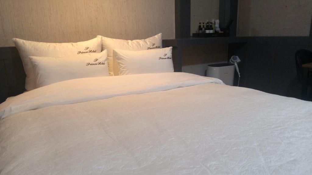 釜山普林斯汽车旅馆的一张白色大床,配有白色床单和枕头