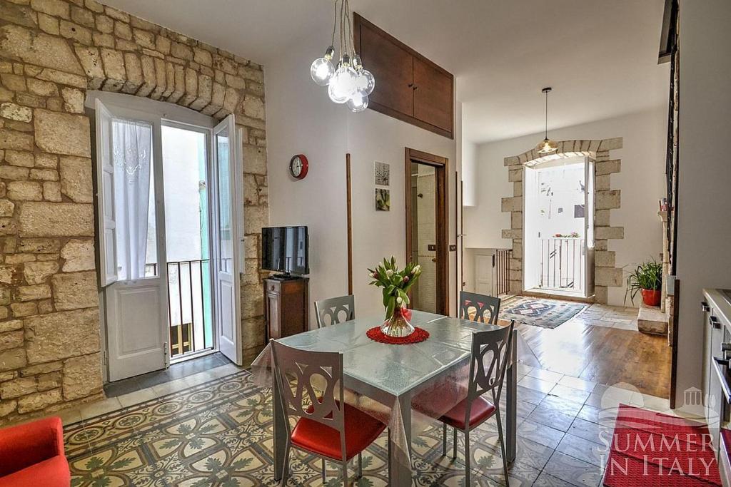 图里Antiche Mura Apartments "Nel Cuore della Puglia"bivani, cucina, terrazzo的一间设有玻璃桌和椅子的用餐室
