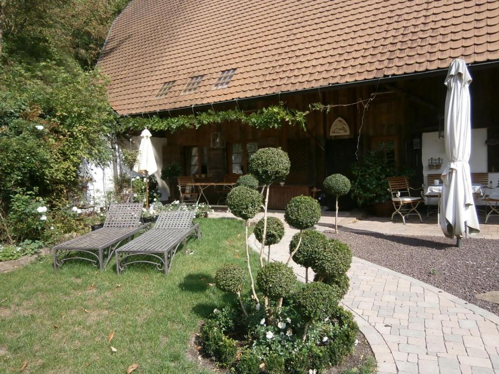 SchuttertalVier Jahreszeiten Idyll的花园设有2张长椅和遮阳伞