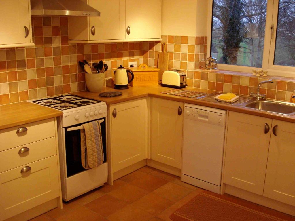 斯特劳德Bobby's Nook的厨房配有白色橱柜和炉灶烤箱。