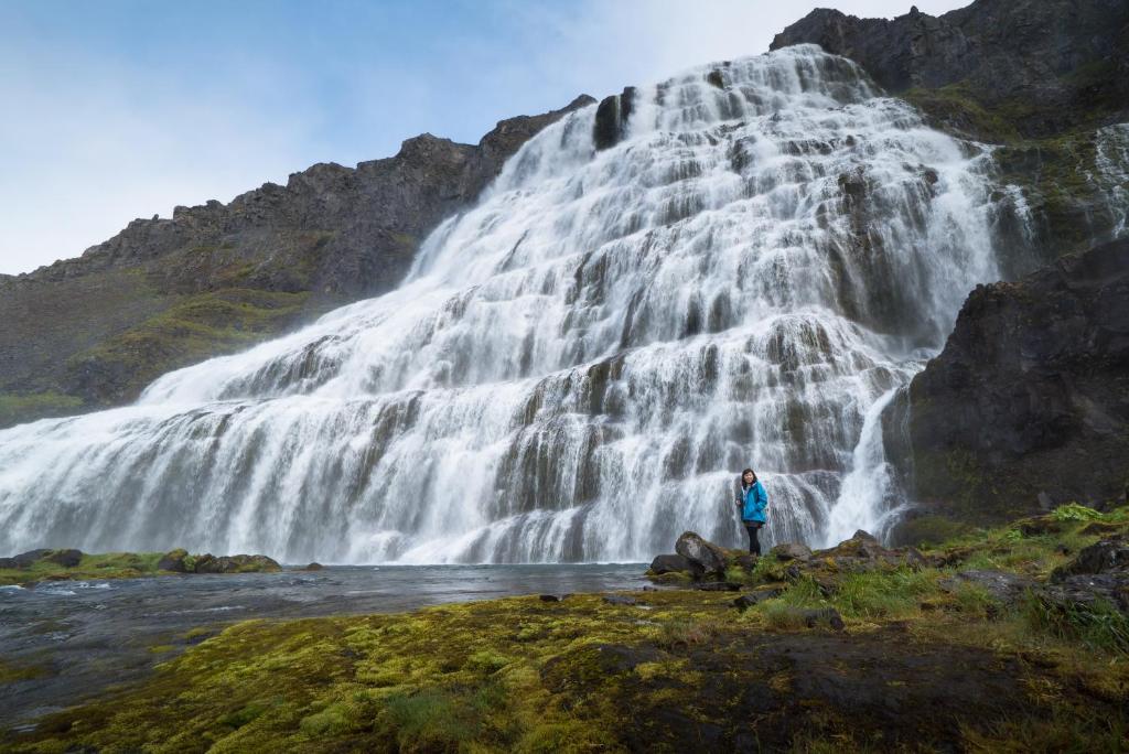 SuðureyriFisherman Guesthouse Sudureyri的站在瀑布前的人