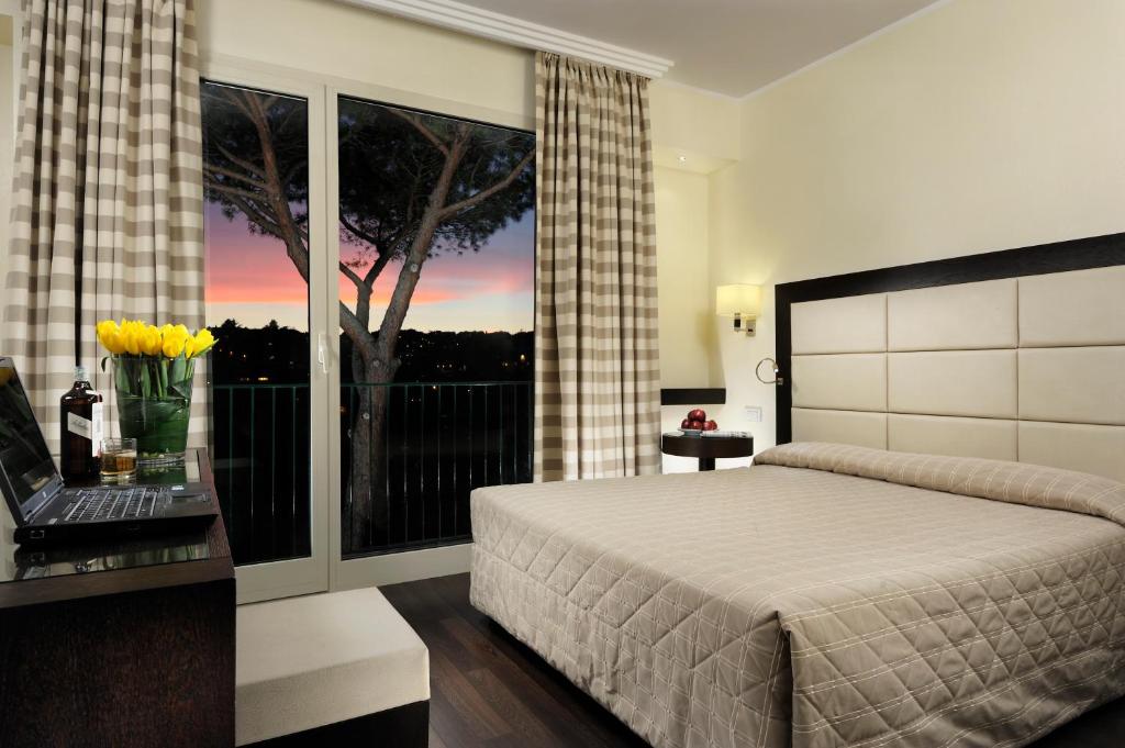罗马玛丽亚蕾佳娜别墅酒店的一间卧室设有一张床,窗户有树