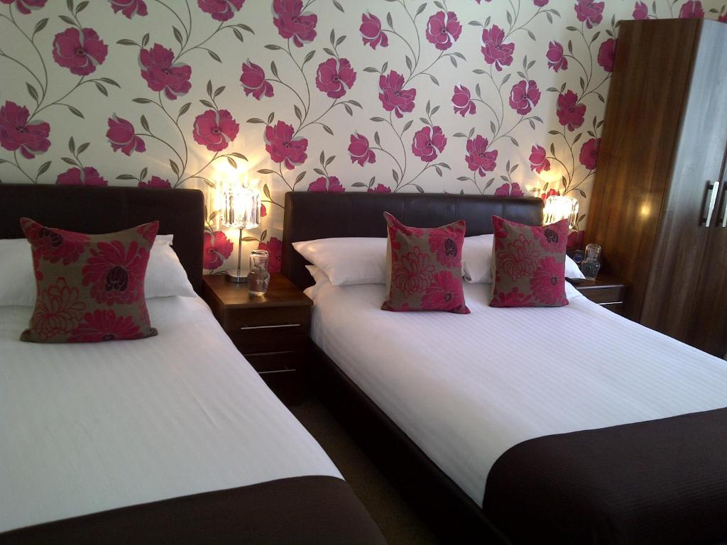 海斯廷斯森拉克旅馆的墙上有粉红色花卉的房间里,有两张床