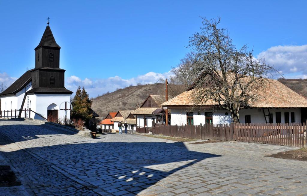 霍尔洛克Nefelejcs Vendégház Hollókő的一座小教堂,有栅栏和鹅卵石街道