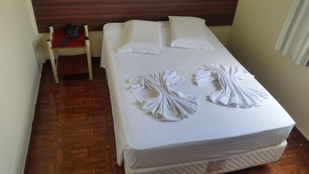 库里提巴Hotel Piratini的配有白色床单和枕头的宿舍间内的一张床位