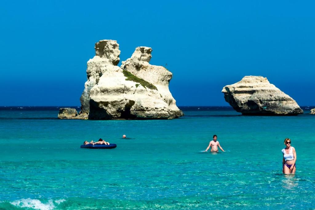 托里德欧索Casa al mare Olimpia的两个大岩石附近水中的人
