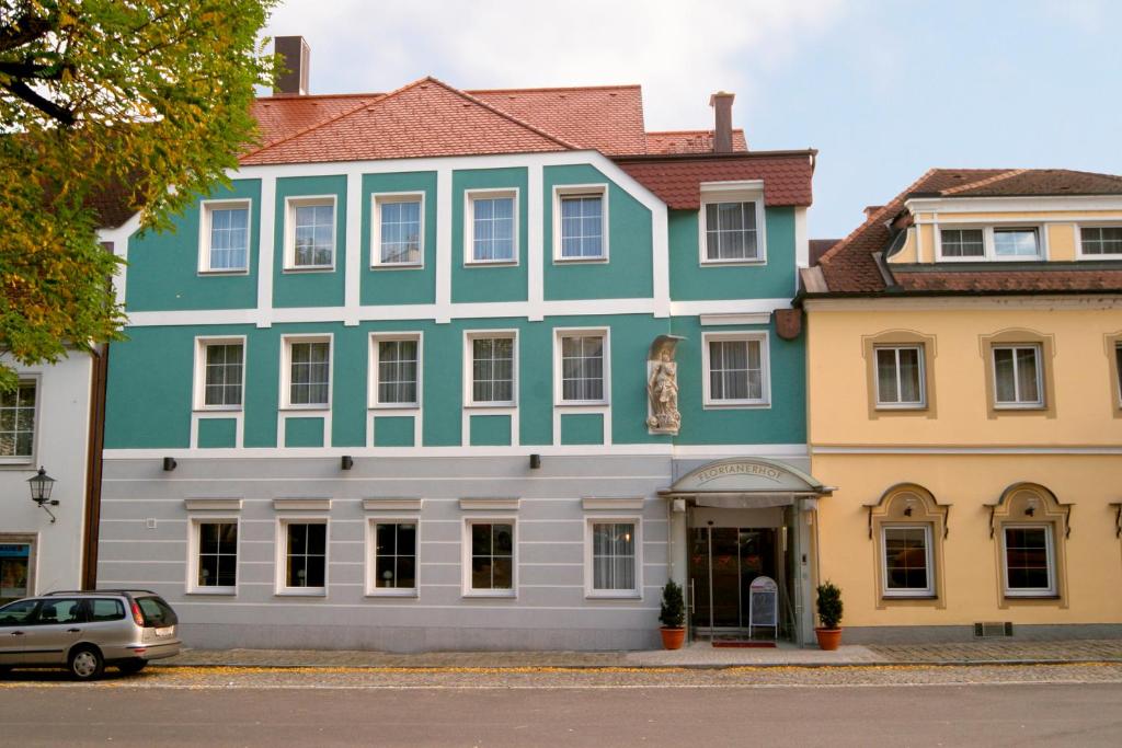 Markt Sankt Florian弗洛瑞安尔霍夫酒店的一座蓝色和白色的大建筑,前面有停车位