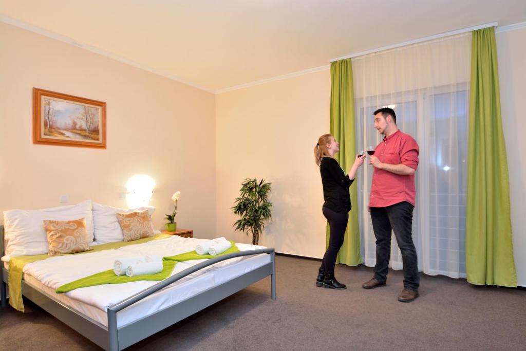 瑙吉奥塔德Viktória Wellness Hotel的一位男人和女人站在酒店带床的房间