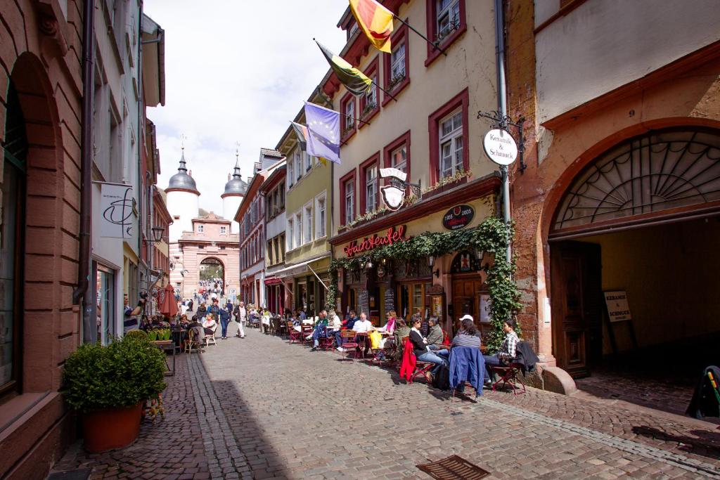 海德堡海克特夫餐厅酒店的一条街上,人们坐在小巷的桌子上