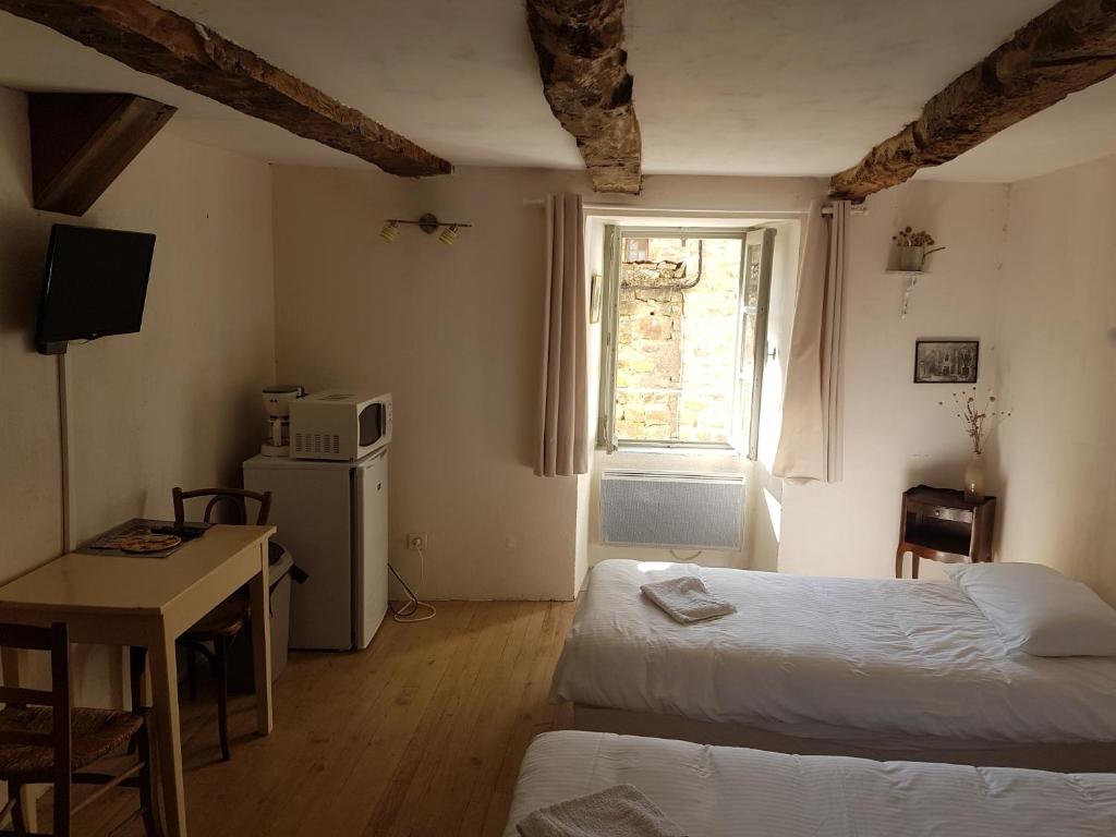 圣莱伊德苏La maison d'Angèle的一间卧室设有两张床、一张桌子和一个窗口