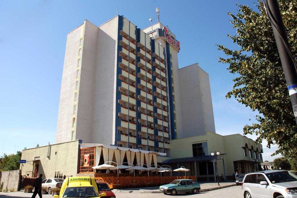 卡缅涅茨-波多利斯基波多利斯基卡米安奈斯七天酒店的一座大型建筑,前面有汽车停放