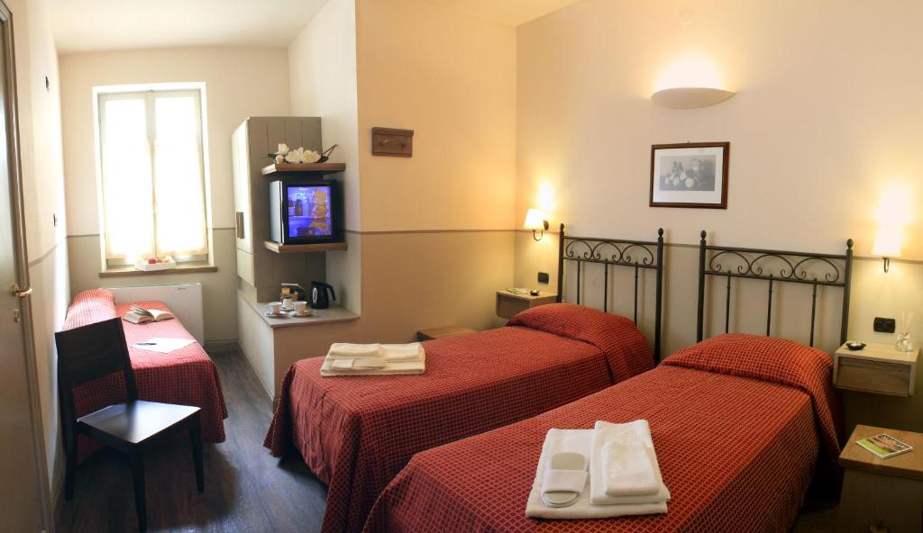 诺尔恰Albergo Benito的酒店客房设有两张床和电视。