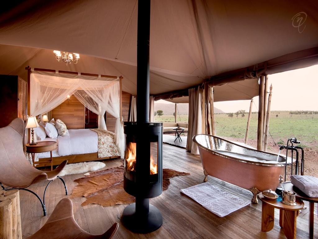 巴纳吉塞伦盖蒂One Nature Nyaruswiga营地的一间卧室配有一张床,帐篷内设有一个浴缸