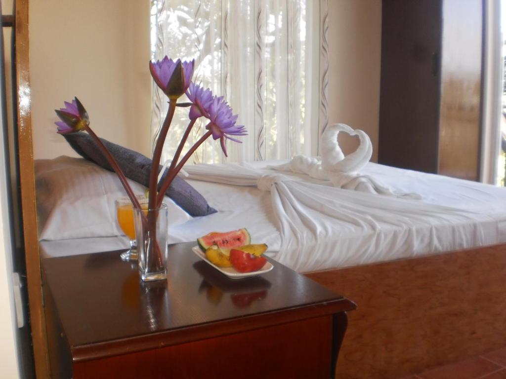 康提威瑟斯彭山林小屋的一张带桌子的床,上面放着一碗水果和鲜花