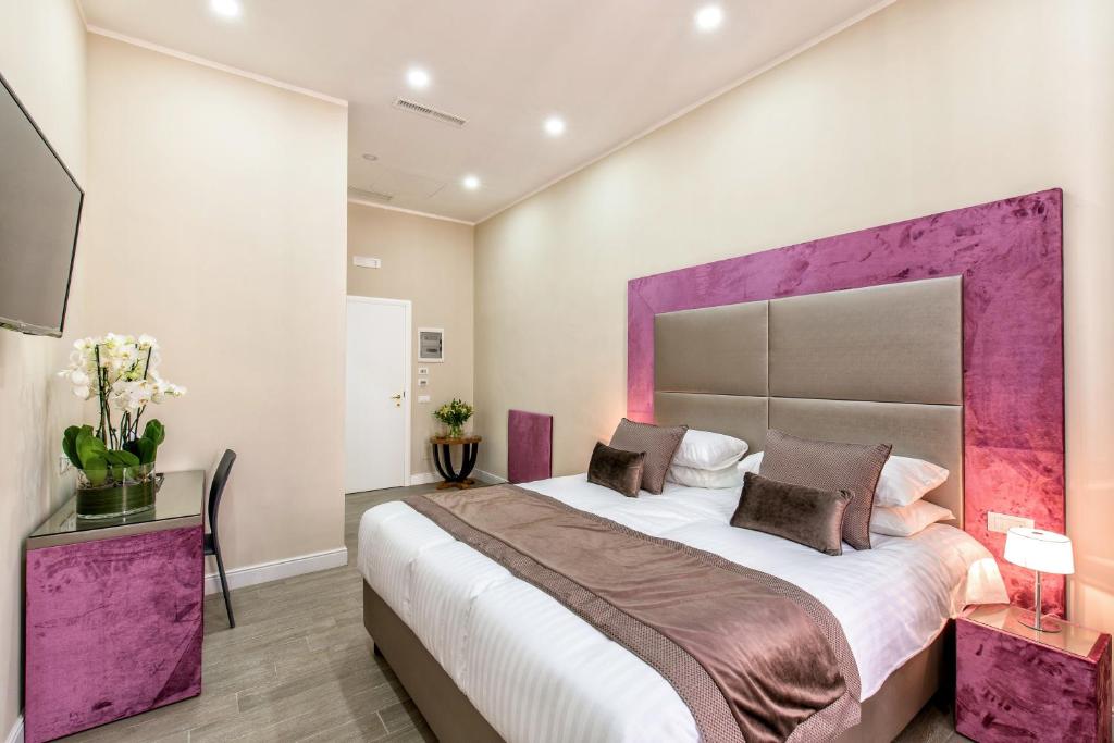 罗马拉格里非布鲁姆公寓旅馆的一间卧室配有一张大床和紫色床头板