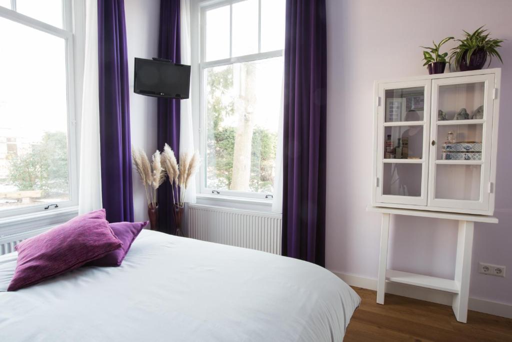 Sint Pancras斯莱彭碧吉德波尔杰梅斯特住宿加早餐旅馆的卧室配有白色床和紫色窗帘