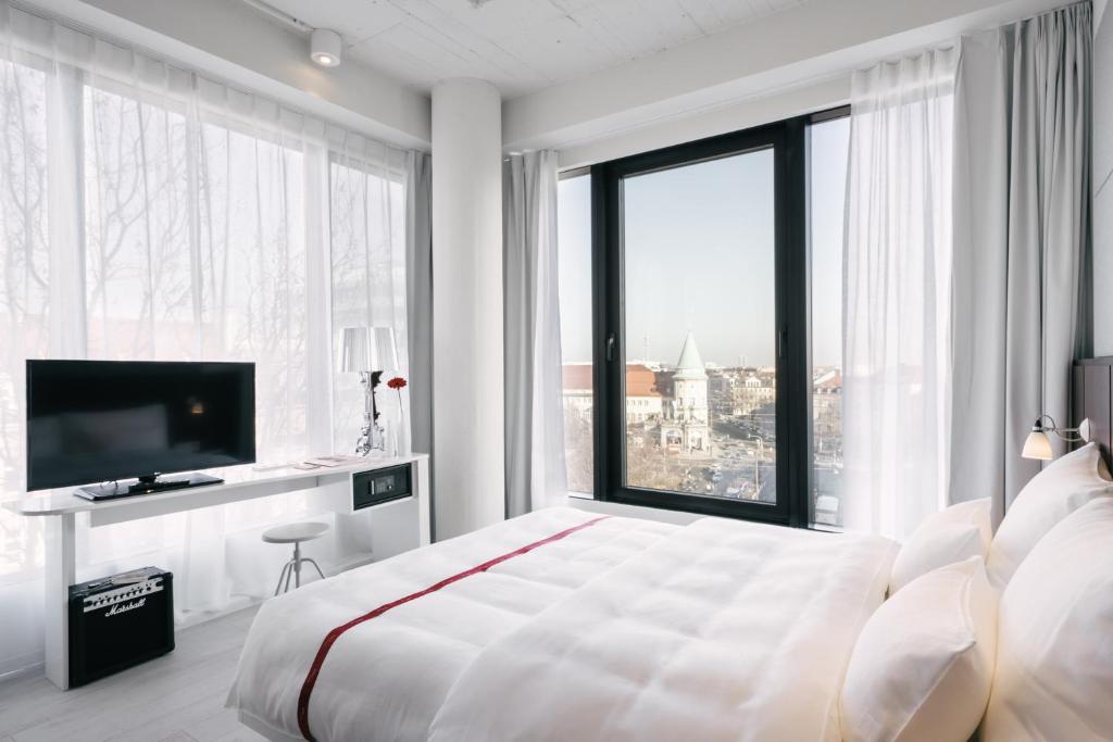 慕尼黑慕尼黑红宝石百合酒店的白色的卧室设有一张大床和一个大窗户