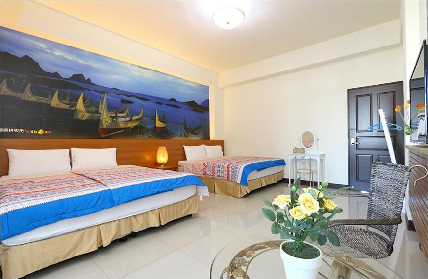 台东台东的家民宿的一间卧室设有两张床,墙上挂着一幅画