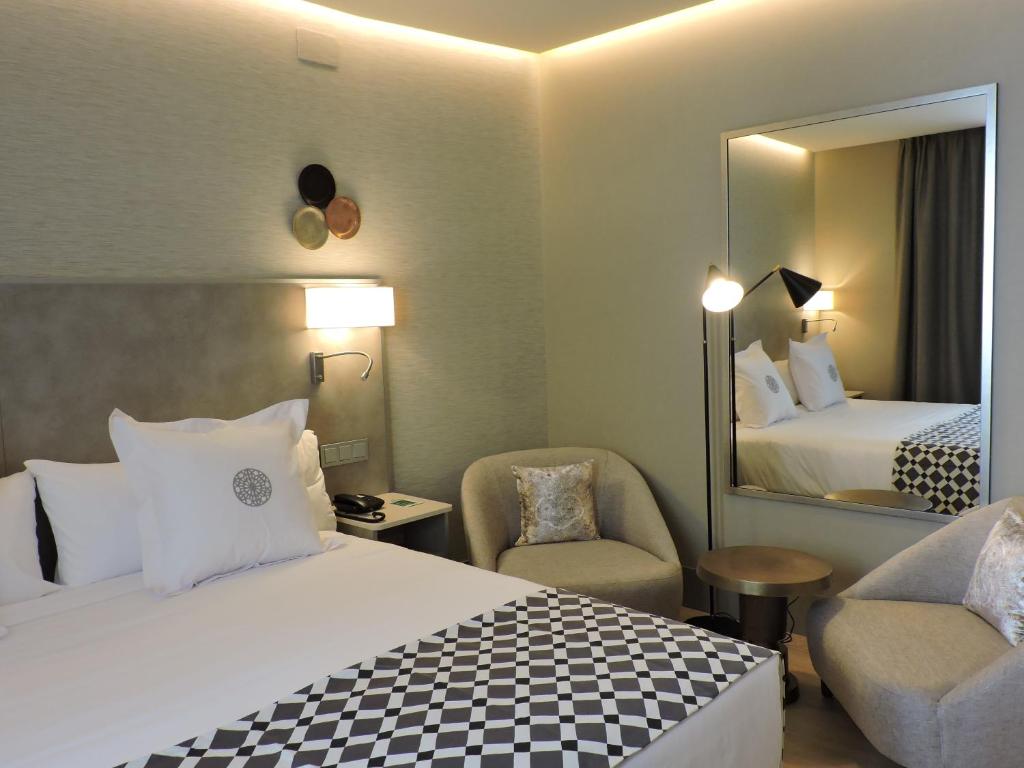塞维利亚塞维利亚美洲酒店的酒店客房,配有床和镜子