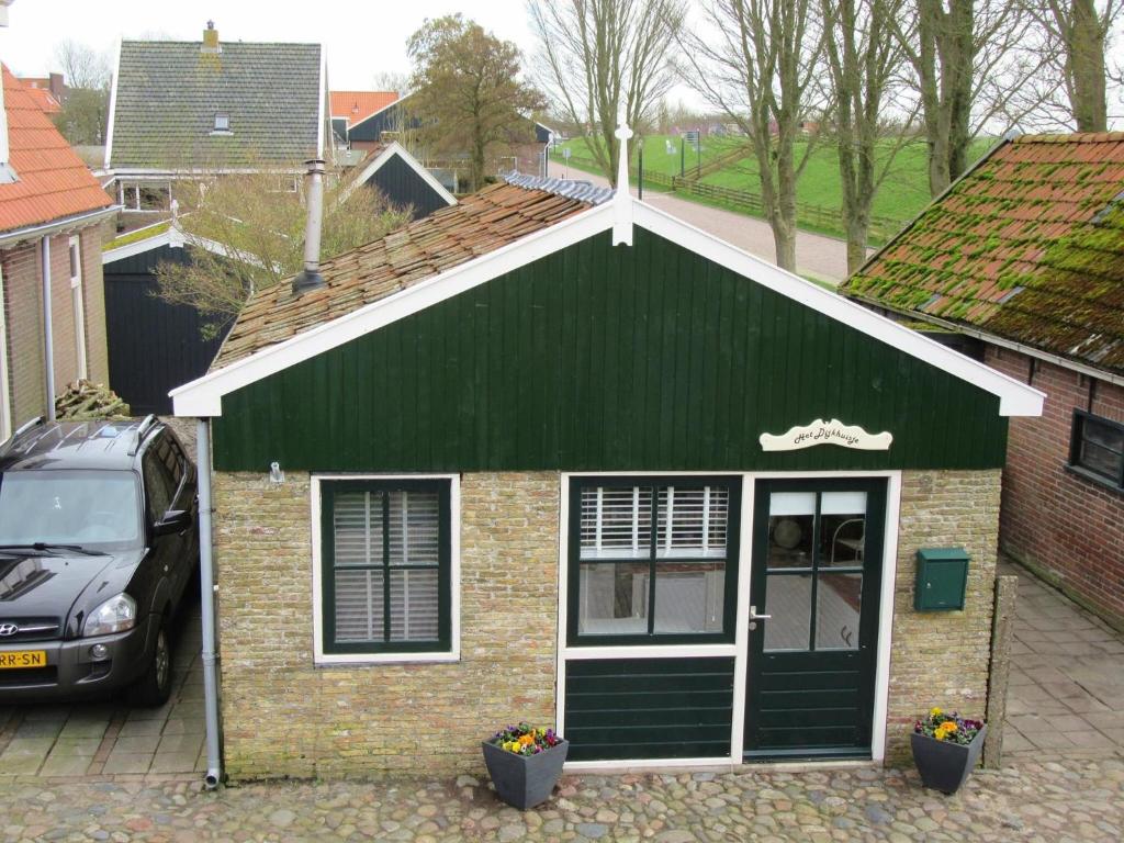 欣德洛彭Het Dijk Huisje的一座绿色的房子,前面有停车位
