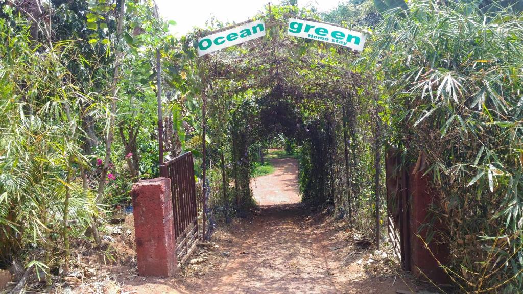 坎努尔海洋绿色喀拉拉邦民宿的带有街标的拱门的花园入口