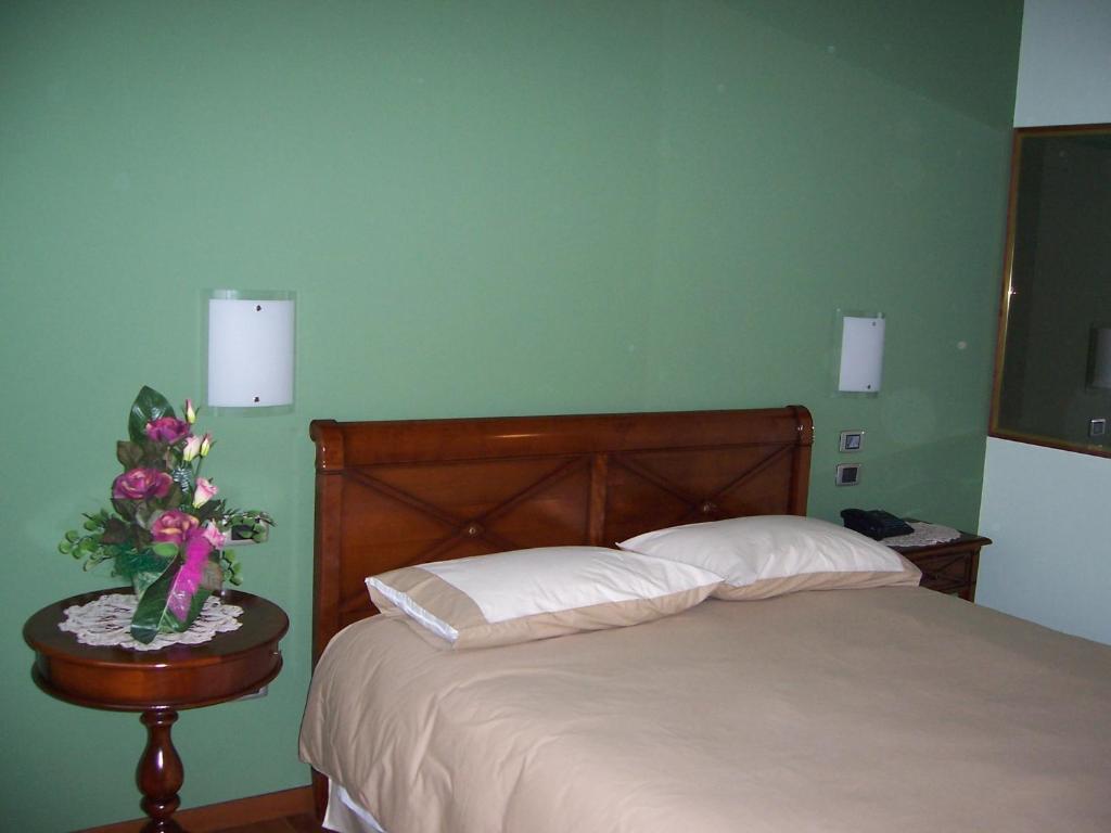 CastelcuccoLocanda da Gerry的一间卧室配有一张床和一张花瓶桌子