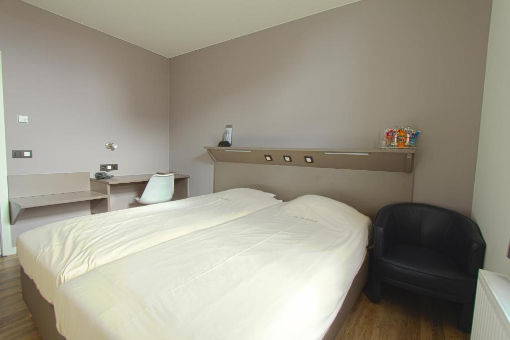 Zoersel德海德布鲁姆酒店的卧室配有白色的床和黑椅