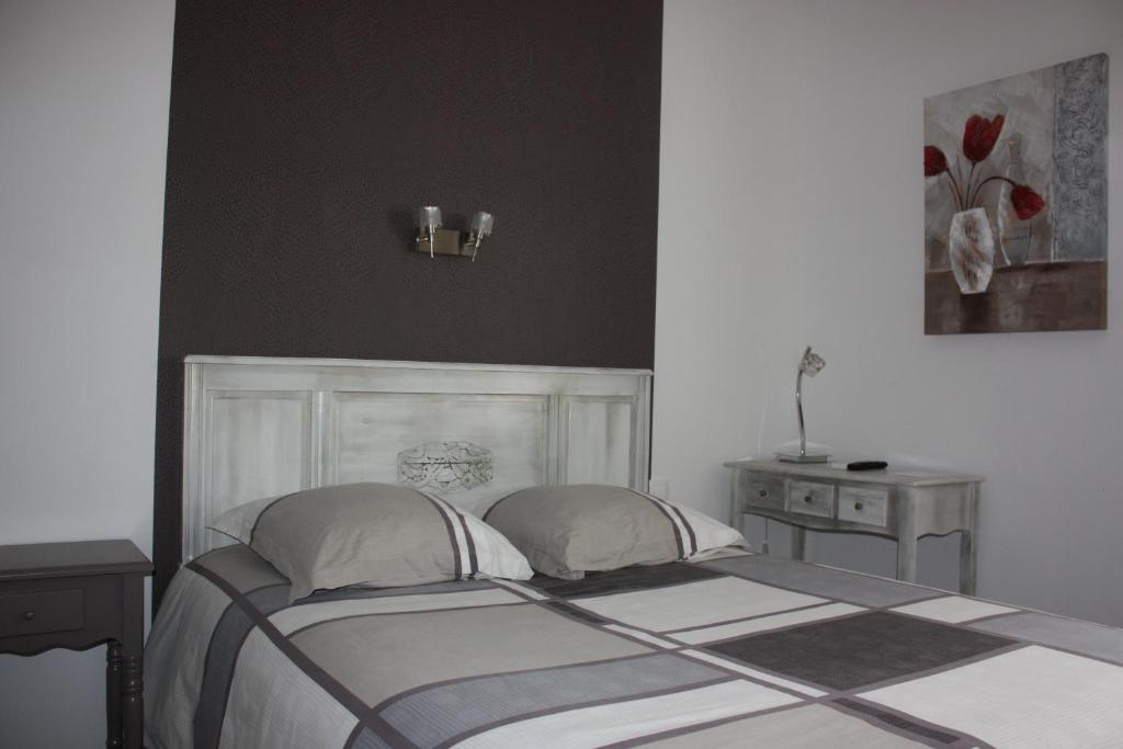 Montaigu-de-Quercy迷笛酒店的一间卧室配有一张带两个枕头和一张桌子的床。