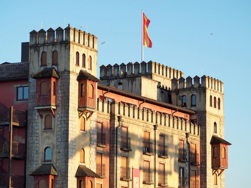 鲁斯特欧洲乐园度假村卡斯蒂罗四星级古堡酒店的一座城堡,在一座建筑的顶部悬挂着旗帜