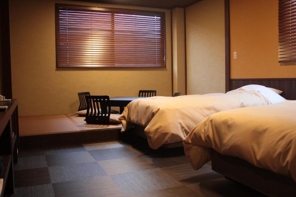 日光常盘传统日式旅馆的一间卧室设有两张床、一张桌子和一个窗口
