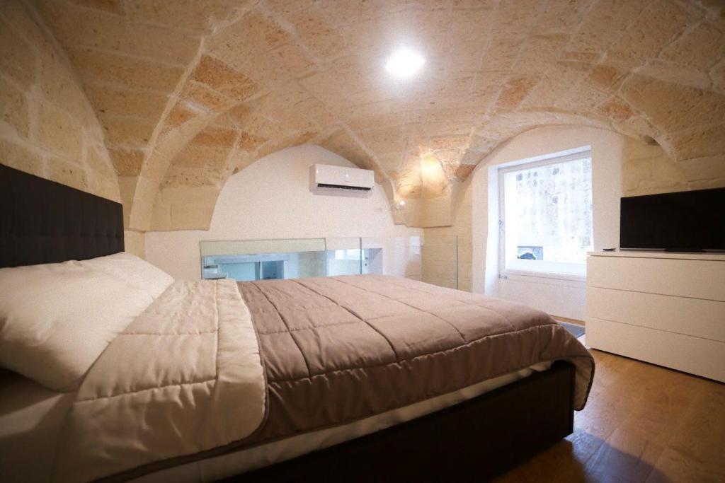 莱切Suite del Teatro Romano的一间卧室设有一张带石墙的大床